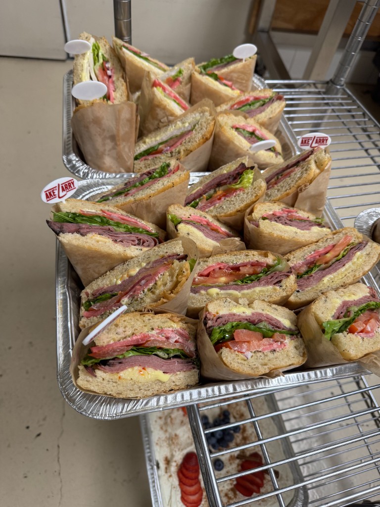 Catering trays of gourmet sandwiches prepared for an event, with Ake'Larry branded picks